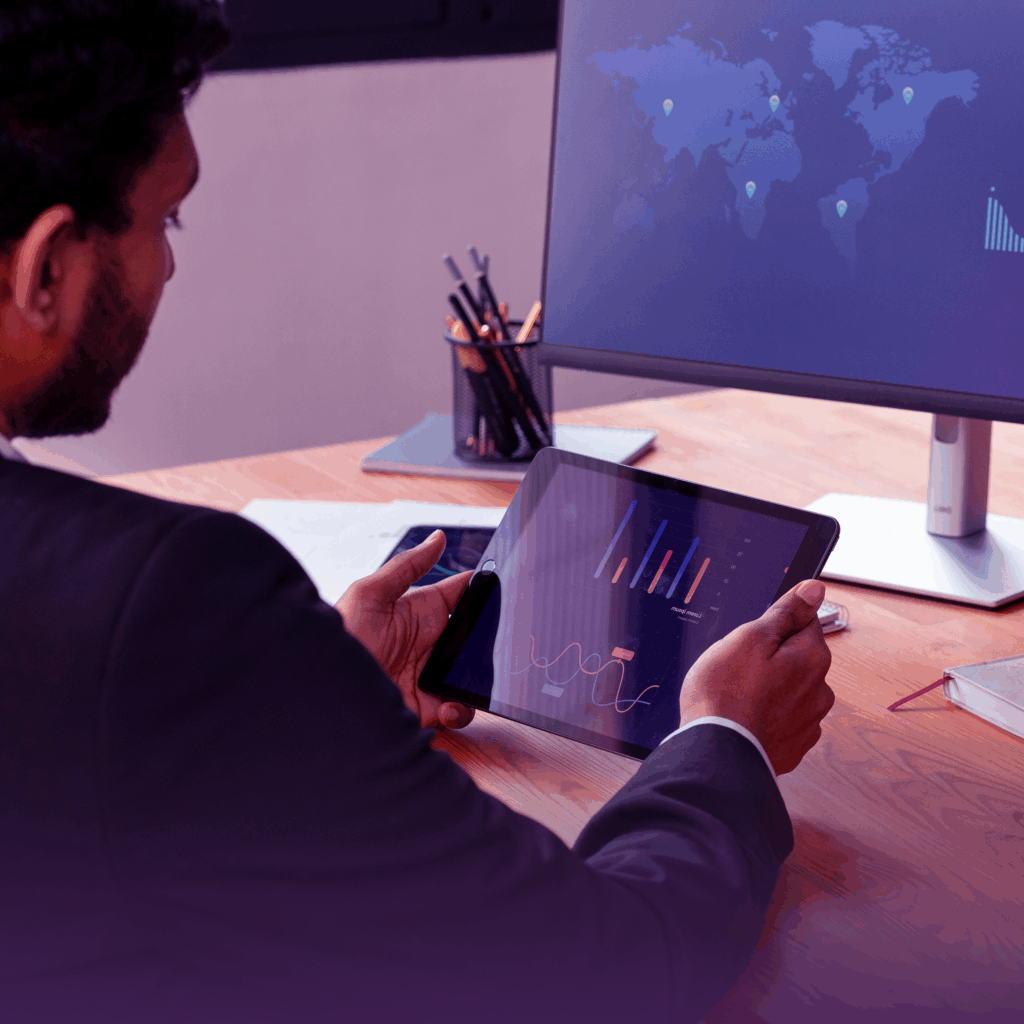 a man sitting in front of a tablet looking on forecasting of risk from tariffs